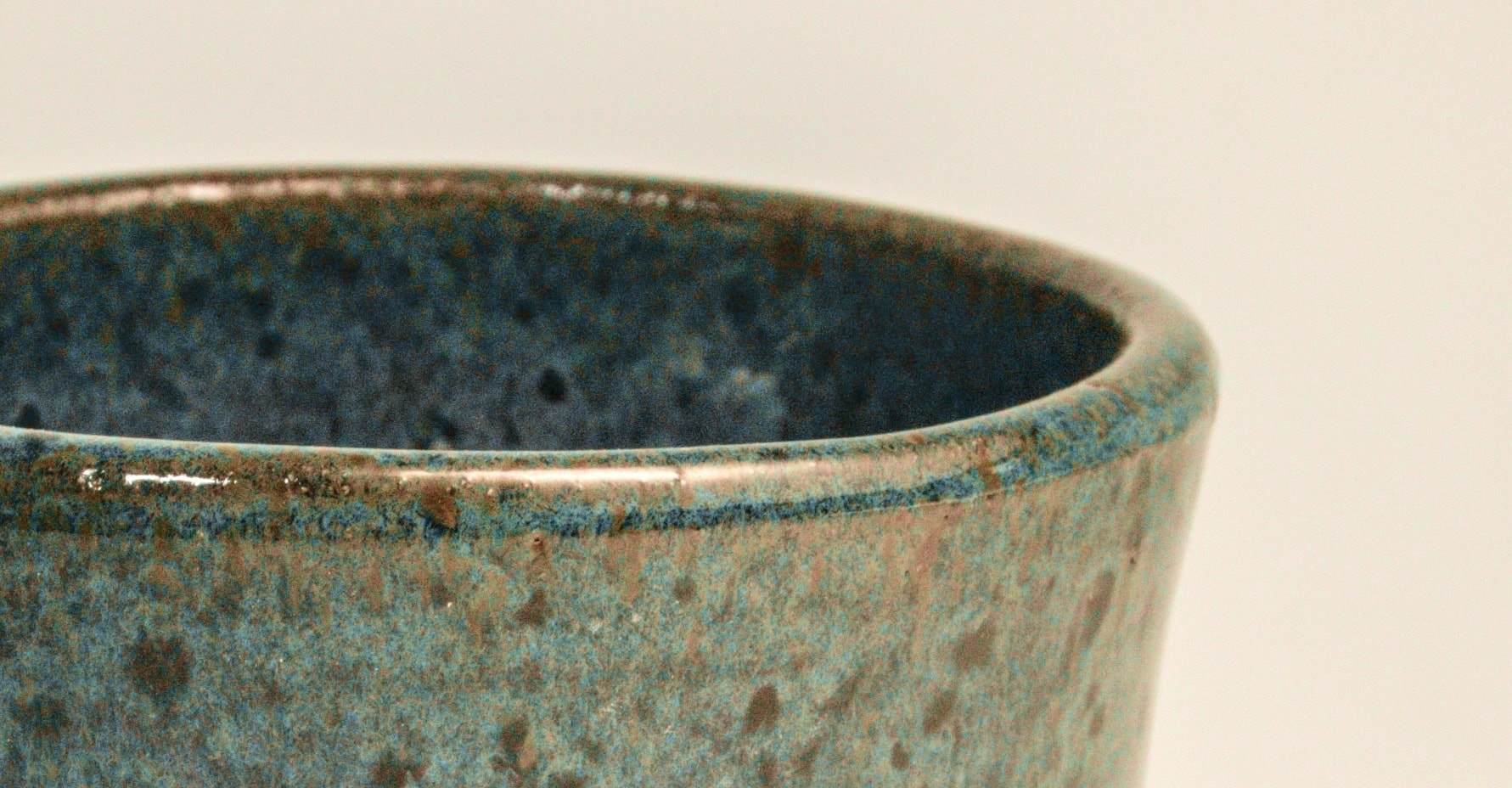 A stack of six hand-glazed Wry Pottery mugs in assorted colors