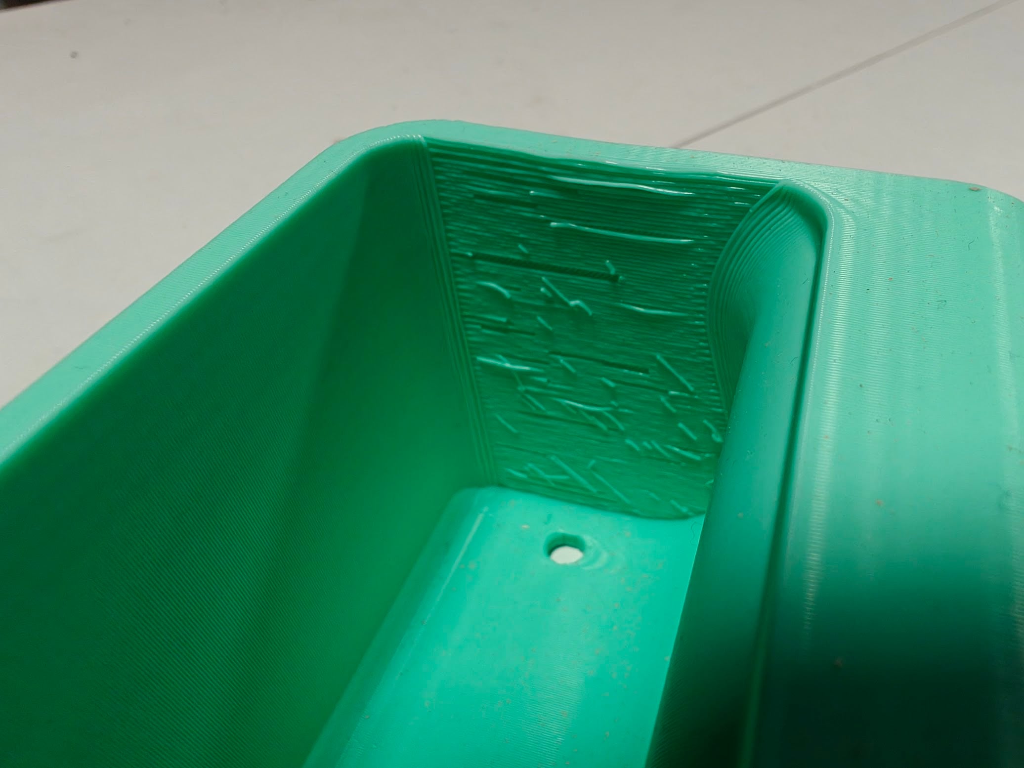 Close-up of the rough interior wall of the tool caddy, showing print ridges and stray filament