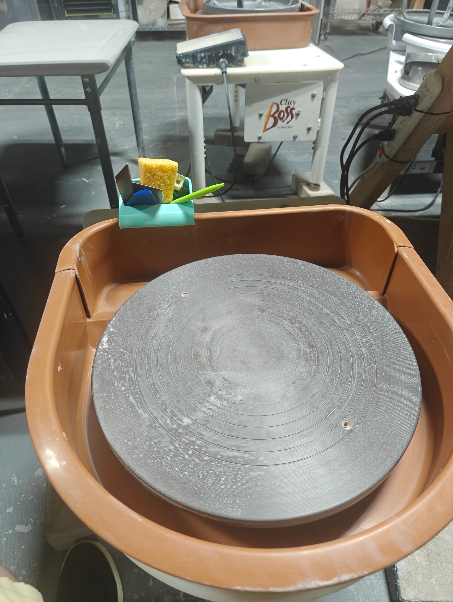 Tool caddy hooked over the splash pan of a pottery wheel